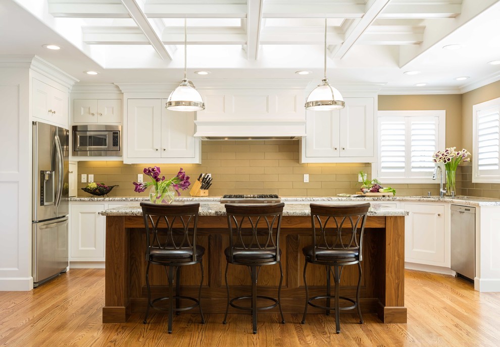 Inspiration for a traditional kitchen in Los Angeles with recessed-panel cabinets, white cabinets, beige splashback, stainless steel appliances, medium hardwood floors and with island.