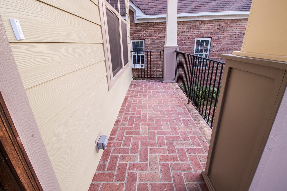 This is an example of a small traditional front yard verandah in Other with brick pavers and a roof extension.
