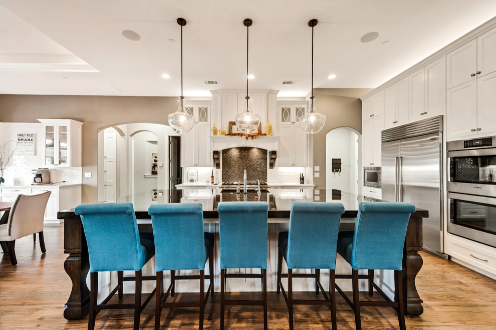 Example of a large transitional light wood floor eat-in kitchen design in Dallas with shaker cabinets, white cabinets, quartzite countertops, stainless steel appliances, an island and brown backsplash