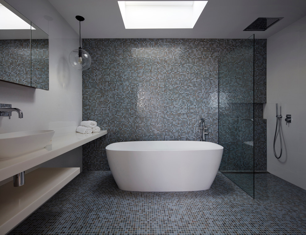 Design ideas for an expansive contemporary master bathroom in Melbourne with mosaic tile, white walls, mosaic tile floors, solid surface benchtops, a freestanding tub, an open shower, a wall-mount toilet, brown tile and a console sink.