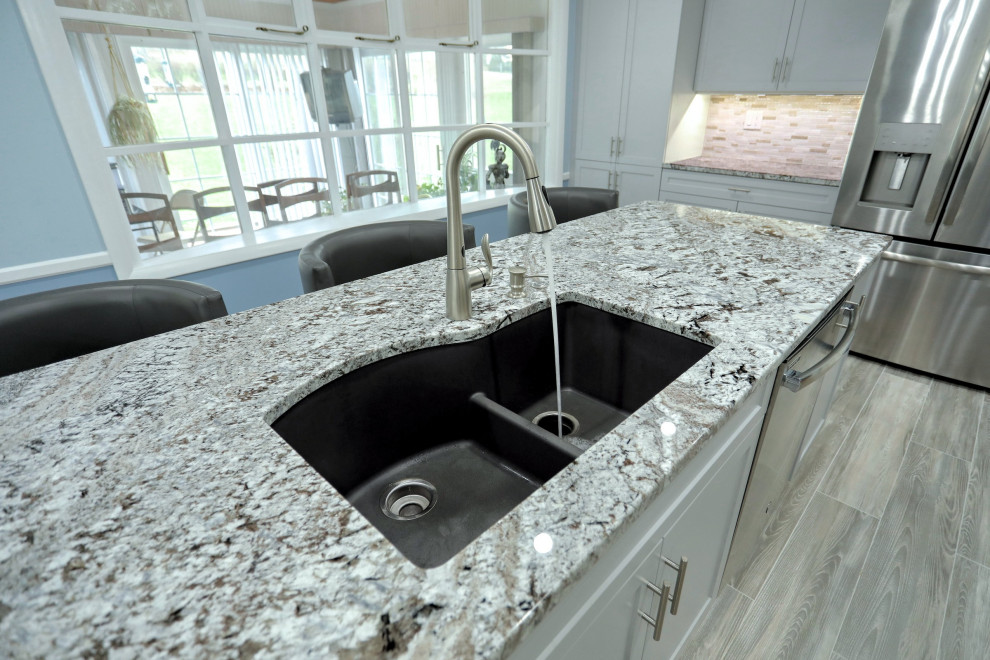 Example of a mid-sized transitional laminate floor and gray floor eat-in kitchen design with a double-bowl sink, shaker cabinets, gray cabinets, granite countertops, multicolored backsplash, mosaic tile backsplash, stainless steel appliances, an island and multicolored countertops