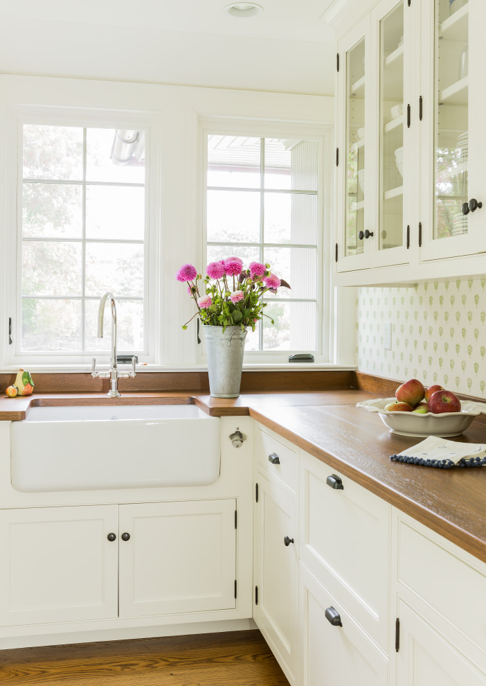 Inspiration for a coastal l-shaped medium tone wood floor and brown floor open concept kitchen remodel in Boston with a farmhouse sink, white cabinets, wood countertops, an island and brown countertops