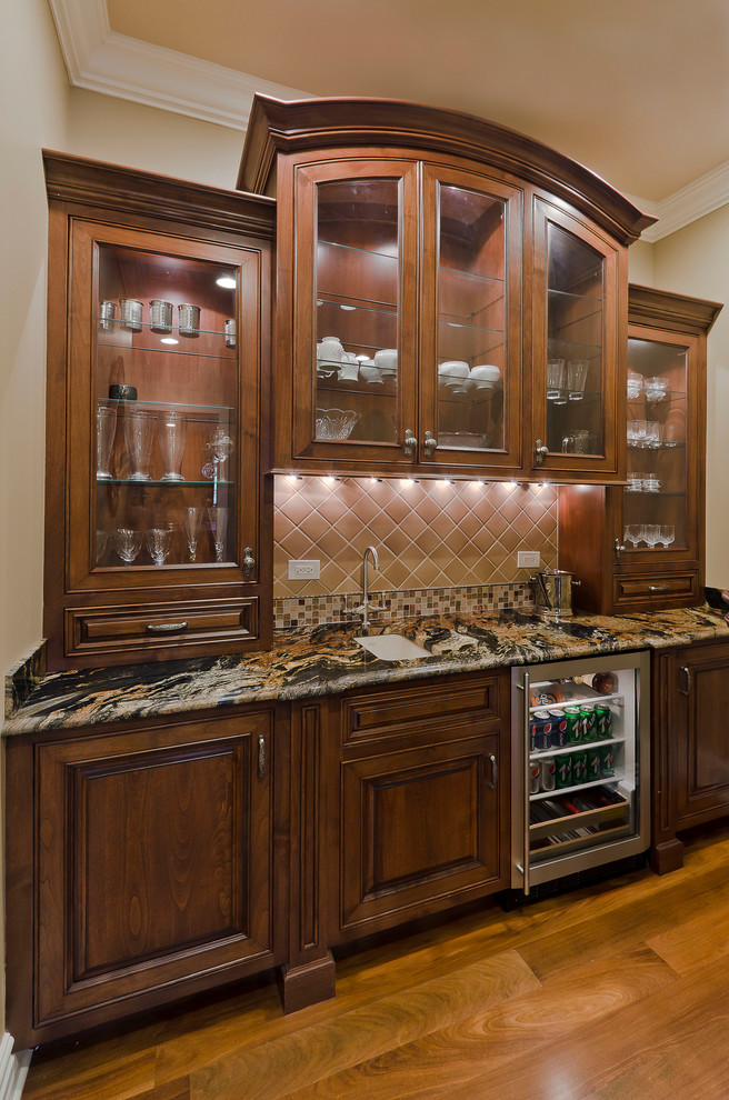 Design ideas for a mid-sized traditional single-wall wet bar in Chicago with an undermount sink, raised-panel cabinets, medium wood cabinets, granite benchtops, multi-coloured splashback, stone tile splashback and medium hardwood floors.