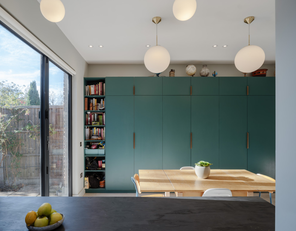 Design ideas for a small modern kitchen/diner in London with an integrated sink, flat-panel cabinets, turquoise cabinets, stainless steel appliances, cork flooring, an island, grey floors, black worktops and exposed beams.