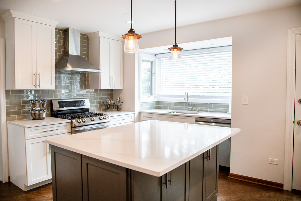 Mid-sized transitional l-shaped separate kitchen in Chicago with an undermount sink, shaker cabinets, grey cabinets, quartz benchtops, glass tile splashback, stainless steel appliances, medium hardwood floors, with island, brown floor and white benchtop.