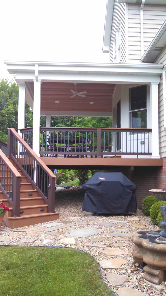 Example of a mid-sized classic backyard deck design with a roof extension