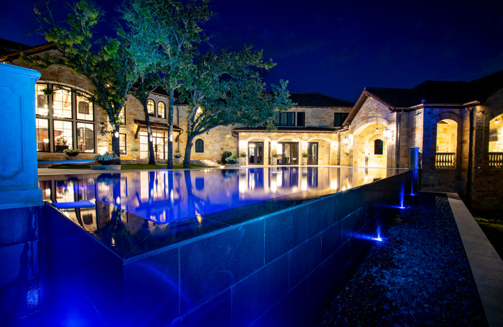 Foto di una grande piscina a sfioro infinito country personalizzata dietro casa con pavimentazioni in pietra naturale