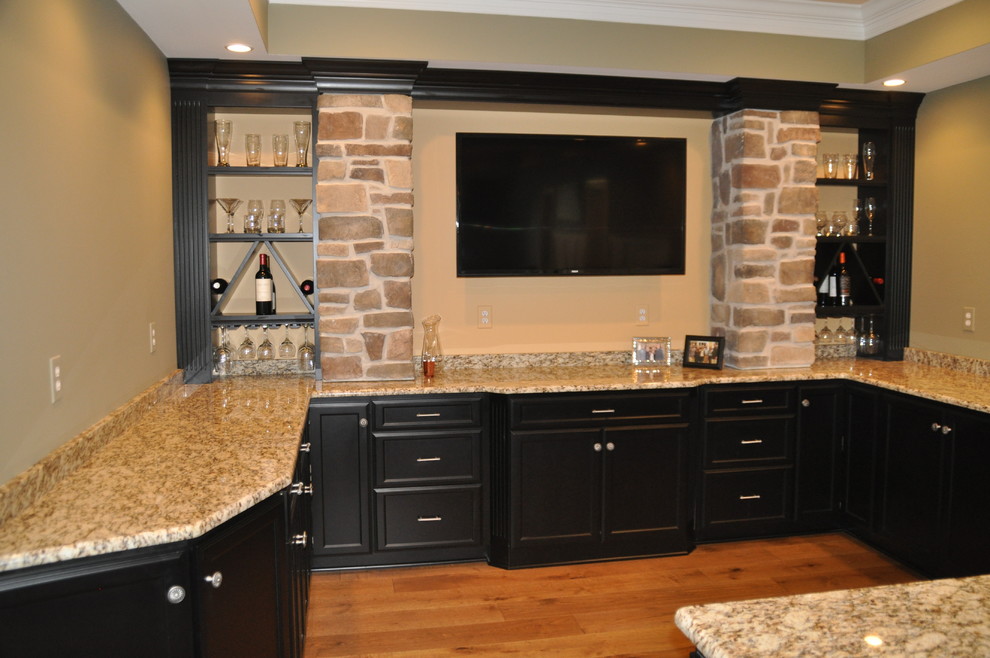 Inspiration for a mid-sized traditional u-shaped seated home bar in Baltimore with an undermount sink, recessed-panel cabinets, black cabinets, granite benchtops and medium hardwood floors.