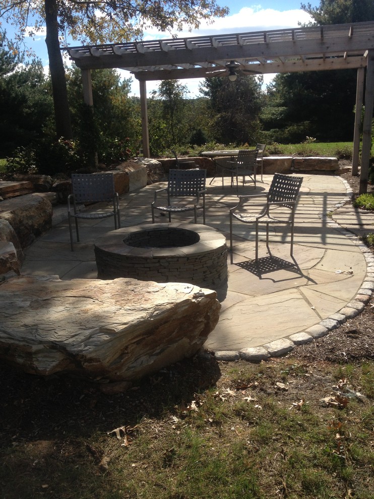 Photo of an arts and crafts backyard patio in Philadelphia with a fire feature, natural stone pavers and a pergola.