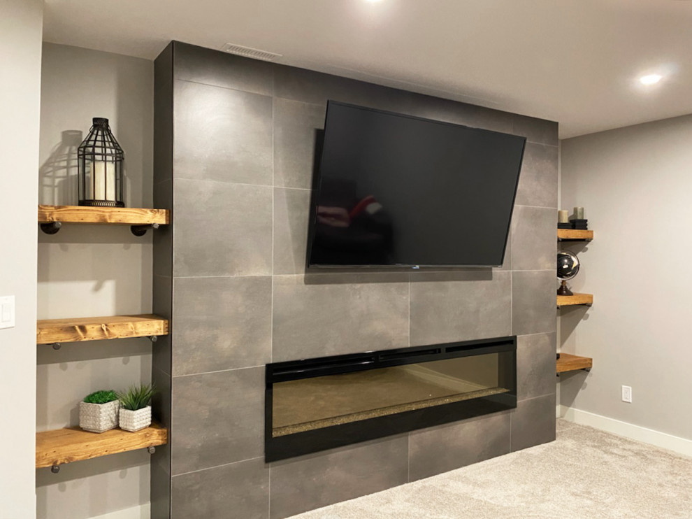 Photo of a medium sized industrial fully buried basement in Calgary with grey walls, carpet, a hanging fireplace, a tiled fireplace surround and grey floors.