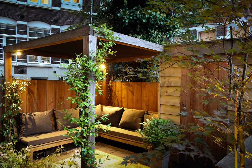 This is an example of a contemporary backyard patio in Amsterdam with a pergola.
