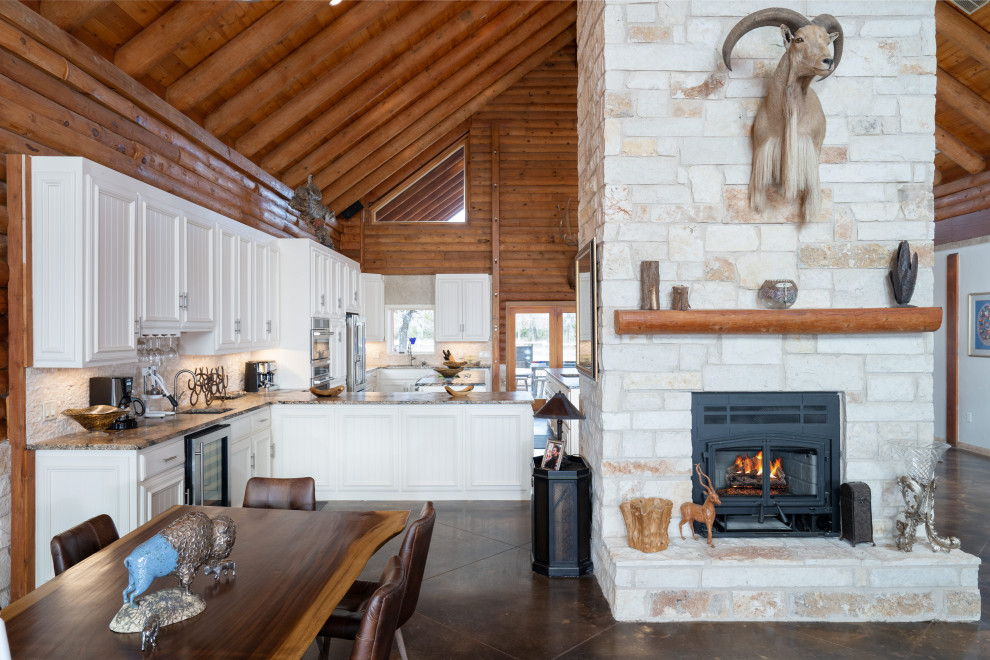 Design ideas for a large open plan dining in Other with concrete floors, a wood stove, a stone fireplace surround, brown floor, exposed beam and wood walls.