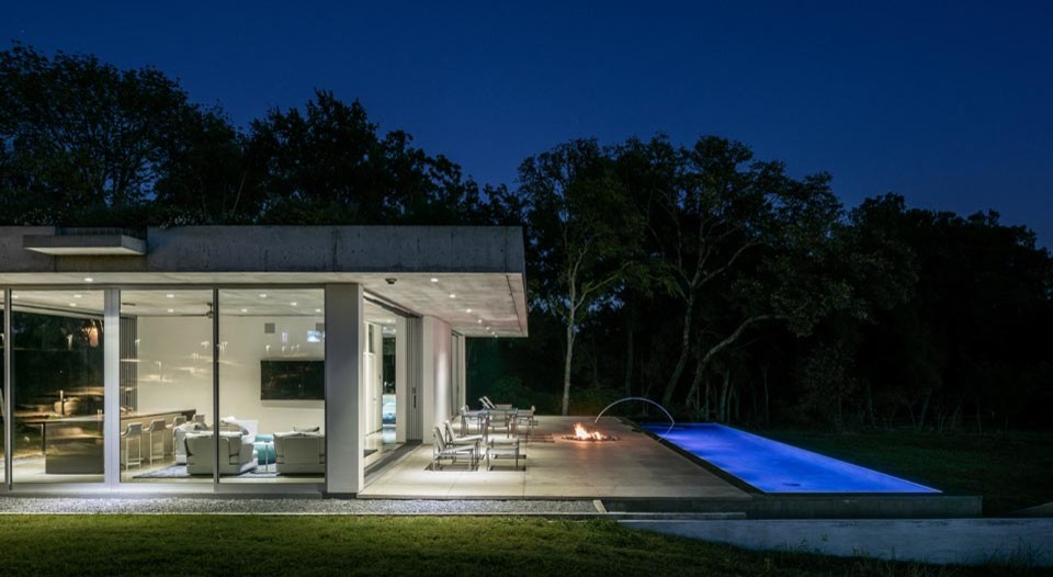 This is an example of a mid-sized modern backyard rectangular lap pool in Dallas with a pool house and concrete slab.