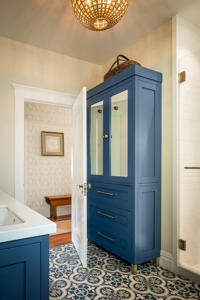 This is an example of a mid-sized traditional kids bathroom in San Francisco with shaker cabinets, blue cabinets, a double shower, a two-piece toilet, white tile, ceramic tile, white walls, cement tiles, an undermount sink, solid surface benchtops, blue floor, a hinged shower door and white benchtops.