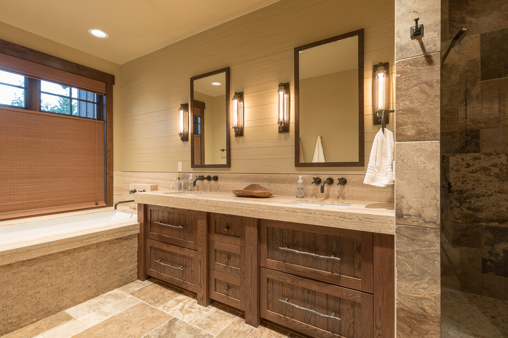 Country master bathroom in Seattle with beige walls, beige floor, shaker cabinets, an undermount tub, beige tile, stone tile, an undermount sink and dark wood cabinets.