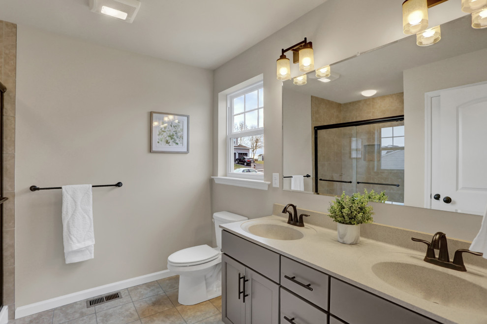 Photo of a mid-sized contemporary master bathroom in Other with shaker cabinets, grey cabinets, a two-piece toilet, beige walls, ceramic floors, an integrated sink, marble benchtops, beige floor, a sliding shower screen and beige benchtops.