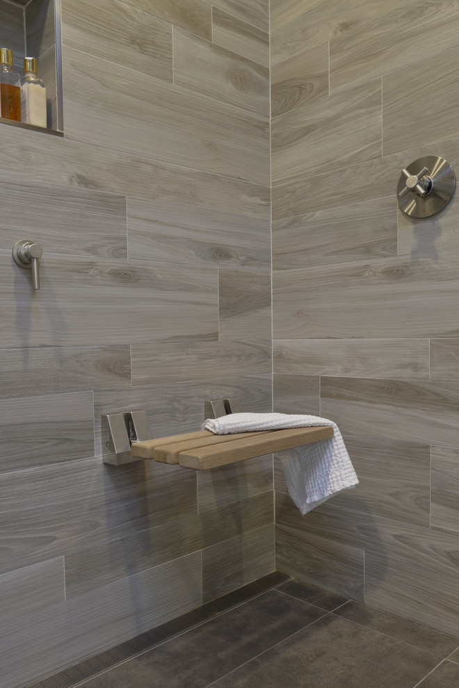 Design ideas for a mid-sized modern master bathroom in New York with furniture-like cabinets, grey cabinets, a double shower, a one-piece toilet, brown tile, porcelain tile, white walls, porcelain floors, an undermount sink, glass benchtops, brown floor and a hinged shower door.