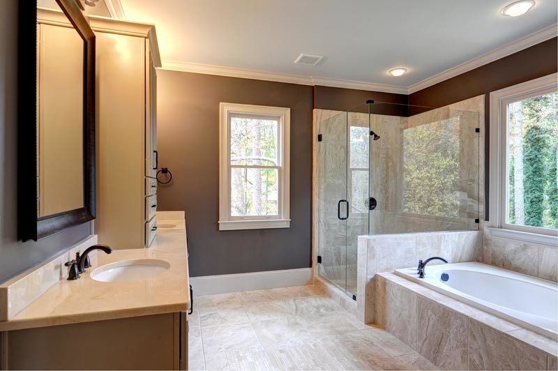 This is an example of a large contemporary master bathroom in Atlanta with beige cabinets, a drop-in tub, a corner shower, beige tile, travertine, brown walls, travertine floors, an undermount sink, solid surface benchtops, beige floor and a hinged shower door.