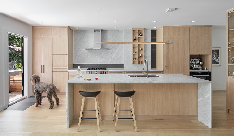 Inspiration for a scandinavian kitchen in Toronto with a double-bowl sink, flat-panel cabinets, light wood cabinets, marble benchtops, grey splashback, marble splashback, light hardwood floors, with island, beige floor and grey benchtop.