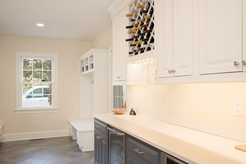 Inspiration for a large contemporary galley utility room in San Francisco with a drop-in sink, raised-panel cabinets, white cabinets, solid surface benchtops, white walls, porcelain floors, a side-by-side washer and dryer and grey floor.