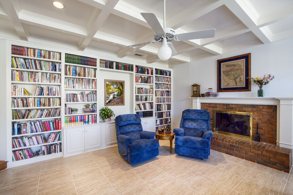 This is an example of a mid-sized transitional open concept family room in Dallas with a library, white walls, ceramic floors, a standard fireplace, a brick fireplace surround, no tv and beige floor.