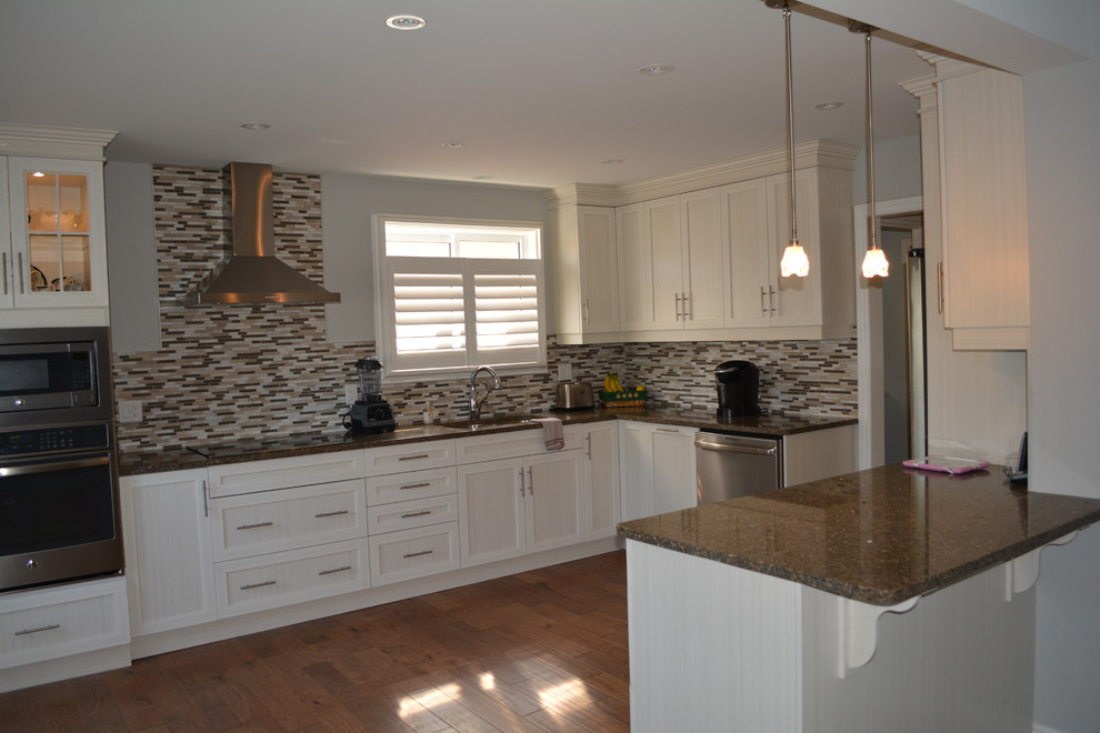 Inspiration for a mid-sized transitional l-shaped medium tone wood floor eat-in kitchen remodel in Toronto with shaker cabinets, white cabinets, stainless steel appliances, a peninsula, a double-bowl sink, granite countertops, multicolored backsplash and matchstick tile backsplash