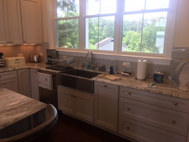 Eat-in kitchen - mid-sized transitional l-shaped dark wood floor and brown floor eat-in kitchen idea with a farmhouse sink, recessed-panel cabinets, gray cabinets, granite countertops, beige backsplash, subway tile backsplash, stainless steel appliances and an island