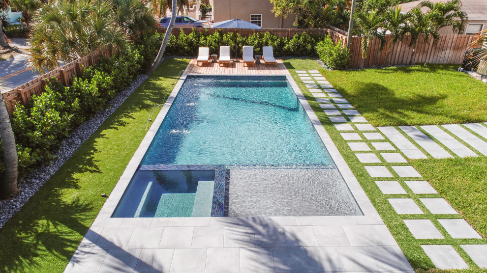Photo of a mid-sized modern backyard rectangular lap pool in Miami with a hot tub and decking.