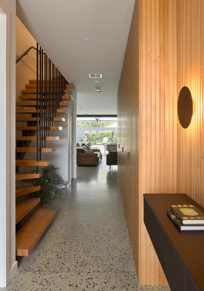 Photo of a mid-sized contemporary entryway in Melbourne with concrete floors, multi-coloured floor and panelled walls.