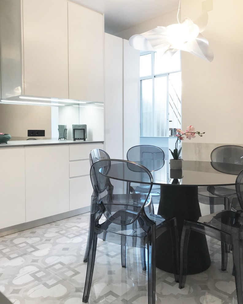 Modern l-shaped open plan kitchen in Madrid with a drop-in sink, flat-panel cabinets, white cabinets, quartz benchtops, grey splashback, porcelain floors, no island and grey floor.