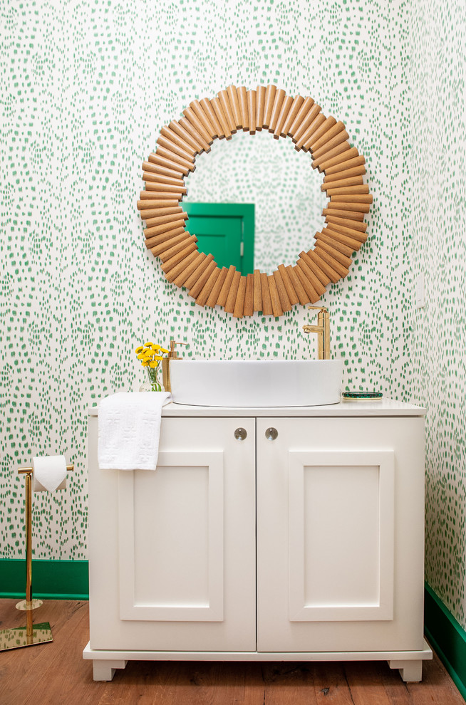 Transitional powder room in Nashville with recessed-panel cabinets, white cabinets, green walls, medium hardwood floors, a vessel sink, brown floor and white benchtops.