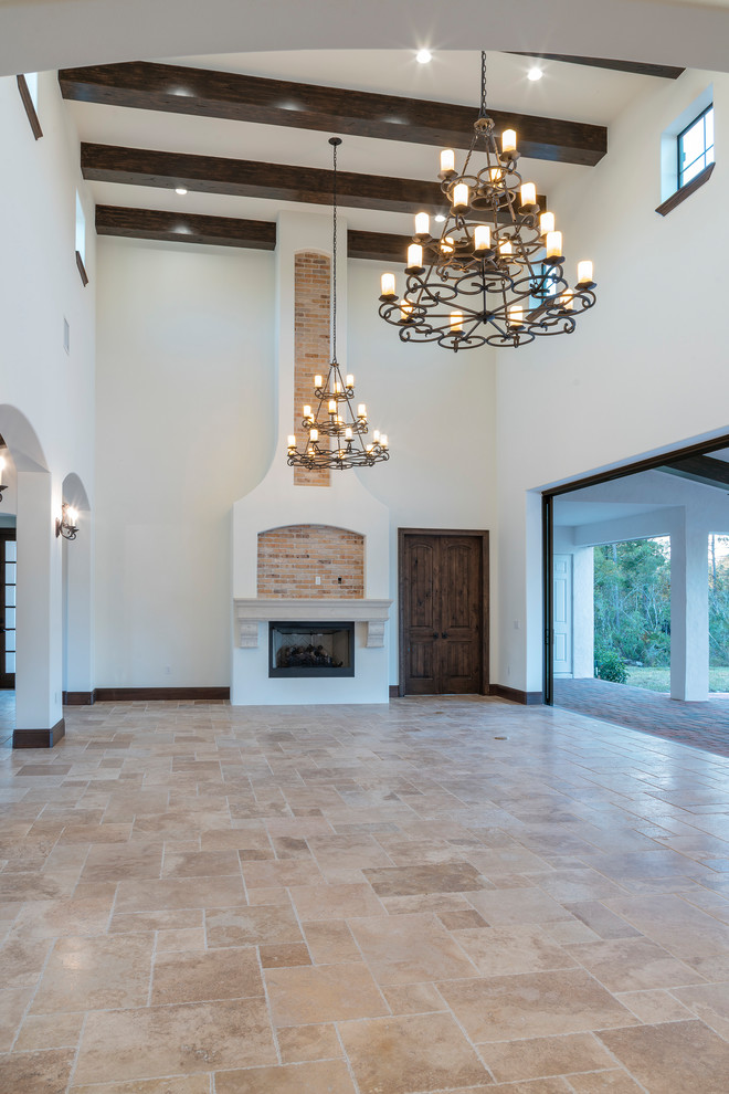 Design ideas for a large mediterranean open concept living room in Orlando with white walls, travertine floors and a standard fireplace.