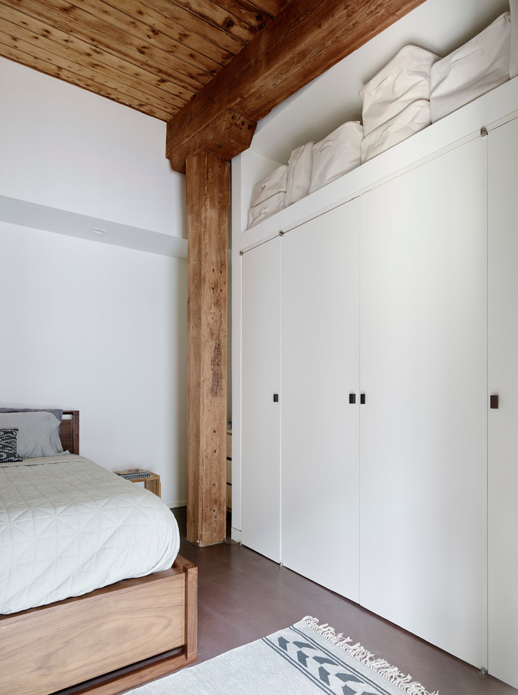 Photo of a mid-sized modern guest bedroom in New York with white walls, concrete floors and no fireplace.