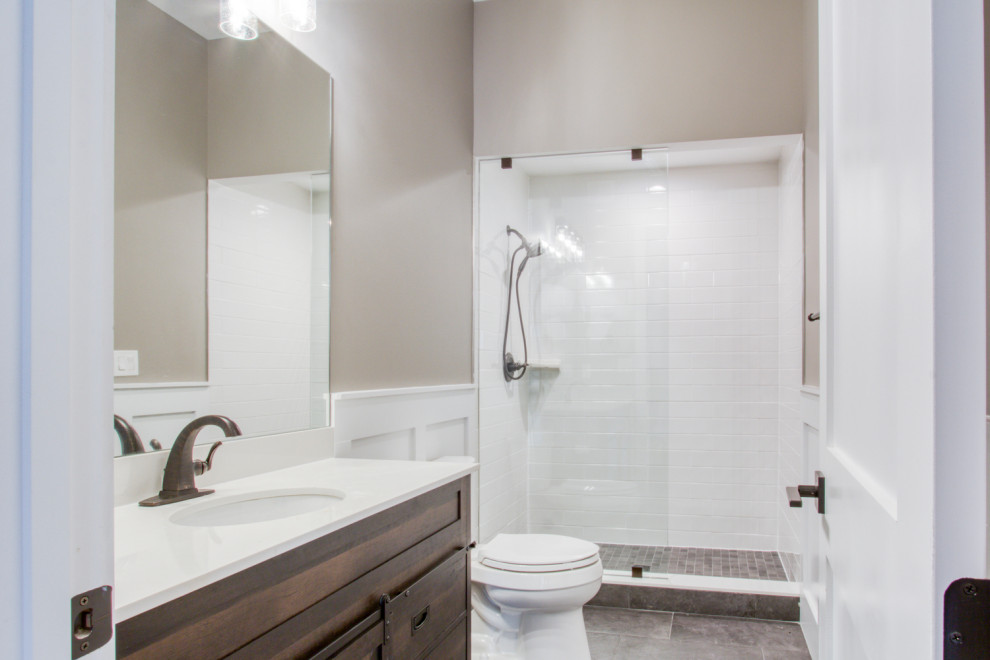 Foto på ett amerikanskt vit badrum med dusch, med bruna skåp, vit kakel, keramikplattor, beige väggar, klinkergolv i keramik, bänkskiva i kvarts, grått golv och med dusch som är öppen