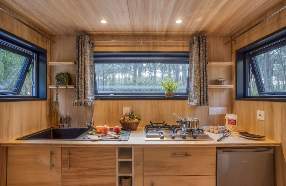 Idéer för små maritima linjära brunt kök med öppen planlösning, med en undermonterad diskho, träbänkskiva, brunt stänkskydd, stänkskydd i trä, ljust trägolv och brunt golv