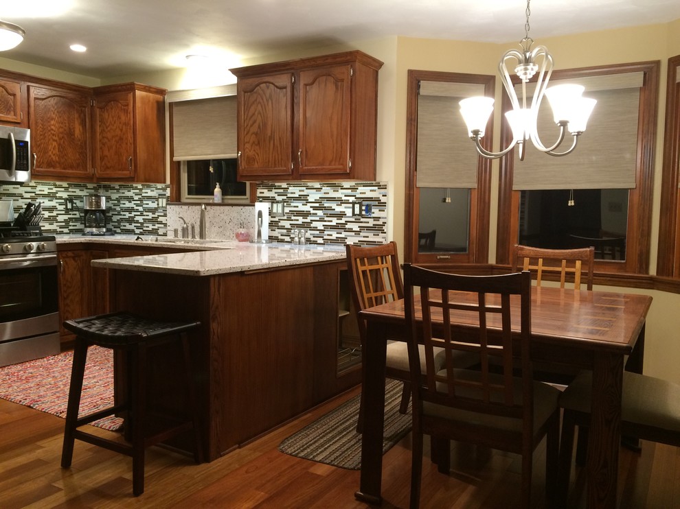 Transitional medium tone wood floor eat-in kitchen photo with an undermount sink, recessed-panel cabinets, medium tone wood cabinets, quartz countertops, brown backsplash, glass tile backsplash and stainless steel appliances