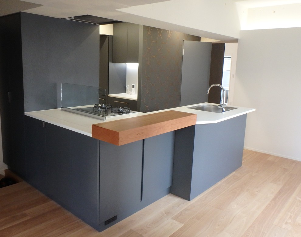 Photo of a mid-sized contemporary l-shaped kitchen pantry in Tokyo with an undermount sink, flat-panel cabinets, grey cabinets, solid surface benchtops, grey splashback, stainless steel appliances and plywood floors.
