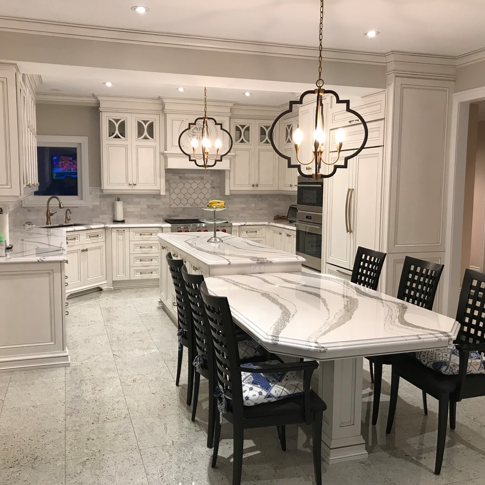 Photo of an expansive traditional u-shaped eat-in kitchen in Toronto with an undermount sink, recessed-panel cabinets, distressed cabinets, quartz benchtops, white splashback, marble splashback, panelled appliances, with island, white floor and white benchtop.