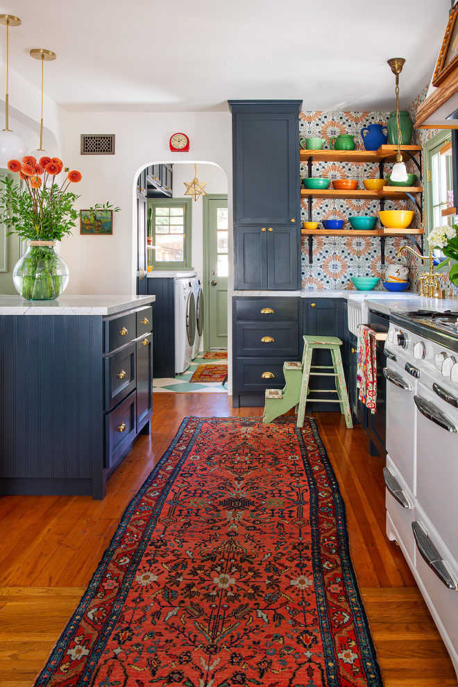 Inspiration for a mid-sized eclectic galley eat-in kitchen in Los Angeles with a farmhouse sink, shaker cabinets, blue cabinets, marble benchtops, multi-coloured splashback, porcelain splashback, white appliances, medium hardwood floors, with island and white benchtop.