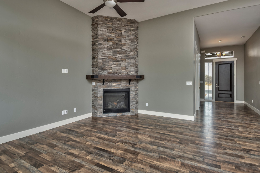 This is an example of a large traditional open concept living room in Other with grey walls, medium hardwood floors, a corner fireplace, a stone fireplace surround and multi-coloured floor.