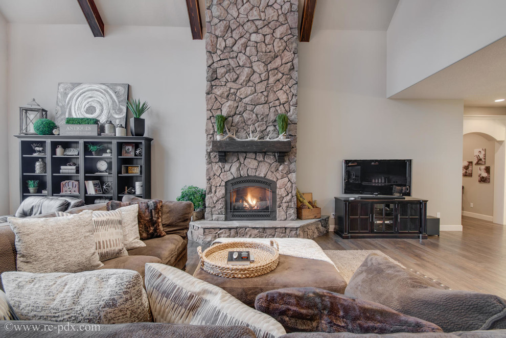 This is an example of a large arts and crafts open concept living room in Portland with beige walls, medium hardwood floors, a standard fireplace, a stone fireplace surround and a freestanding tv.