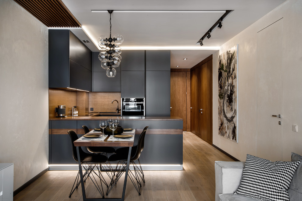 Design ideas for a mid-sized contemporary u-shaped eat-in kitchen in Yekaterinburg with an undermount sink, flat-panel cabinets, grey cabinets, wood benchtops, brown splashback, timber splashback, medium hardwood floors, a peninsula, black appliances, brown floor and brown benchtop.