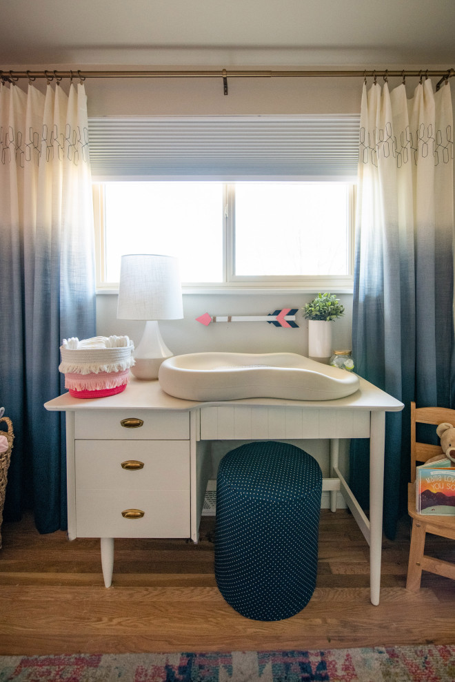Blue & Pink Nursery - Small eclectic girl light wood floor and wainscoting nursery photo in Denver with pink walls