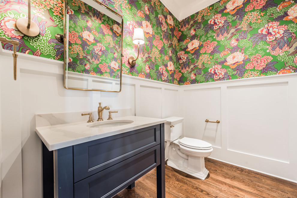 Design ideas for a mid-sized transitional powder room in Charlotte with shaker cabinets, blue cabinets, a two-piece toilet, white walls, medium hardwood floors, an undermount sink, brown floor and beige benchtops.