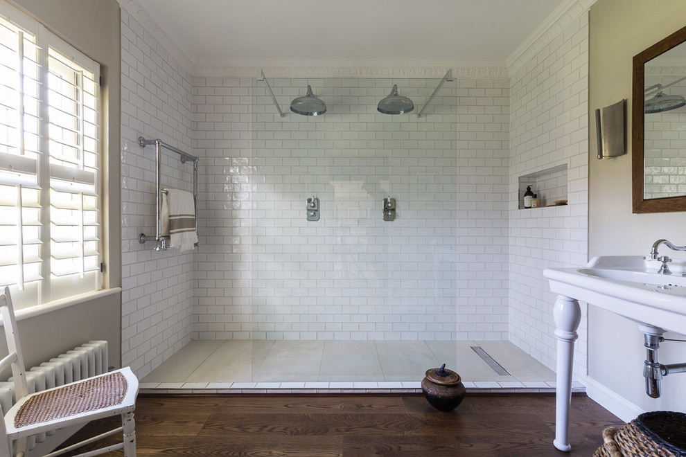 Photo of a large traditional bathroom in London with white tile, beige walls, dark hardwood floors, brown floor, a double shower, subway tile and a console sink.