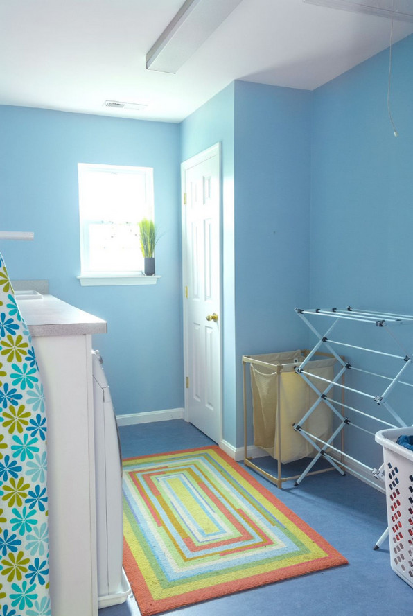 This is an example of a mid-sized transitional single-wall dedicated laundry room in Baltimore with a drop-in sink, solid surface benchtops, blue walls and linoleum floors.