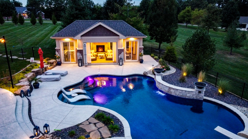 This is an example of a large backyard pool in St Louis with a pool house and stamped concrete.