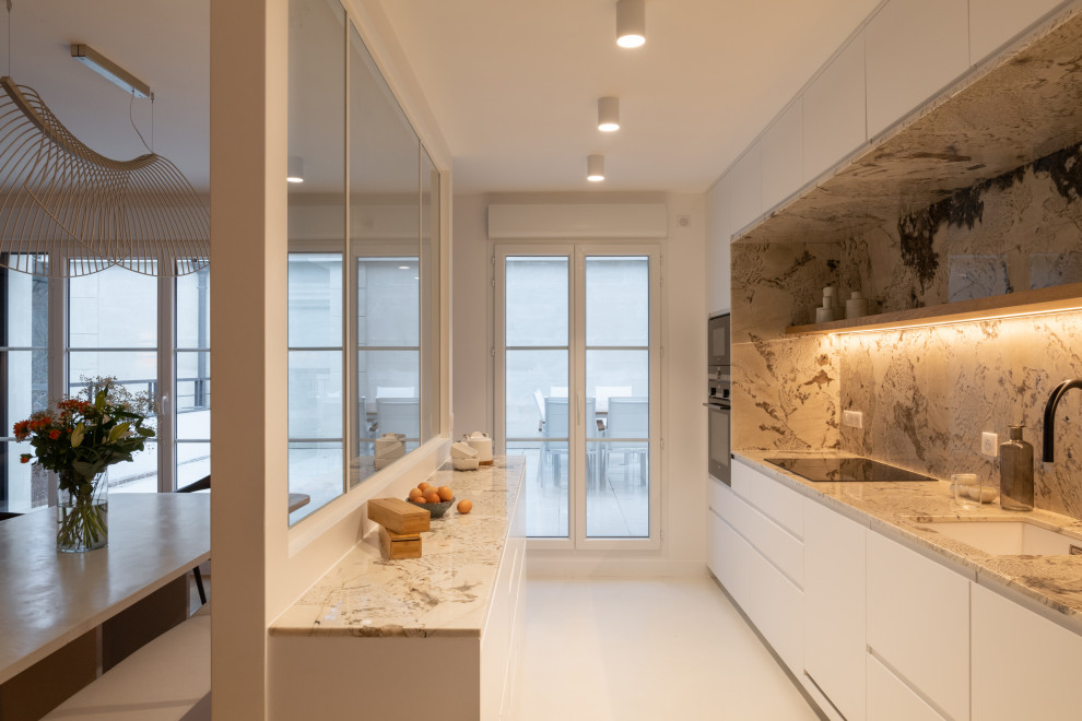Design ideas for a large contemporary galley open plan kitchen in Paris with a single-bowl sink, beaded inset cabinets, white cabinets, granite benchtops, beige splashback, granite splashback, black appliances, concrete floors, white floor and beige benchtop.