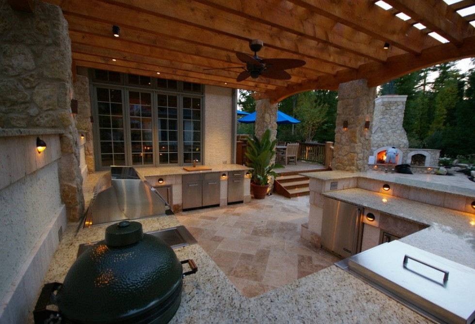 This is an example of a mid-sized mediterranean backyard patio in Tampa with an outdoor kitchen, stamped concrete and a pergola.