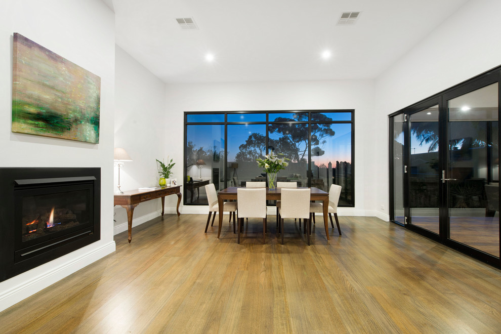 Inspiration for a mid-sized contemporary kitchen/dining combo in Melbourne with white walls and medium hardwood floors.
